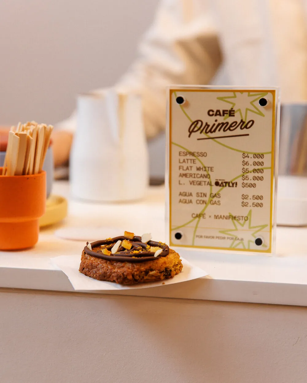 Cartel del Café Primero junto a una cookie en la barra